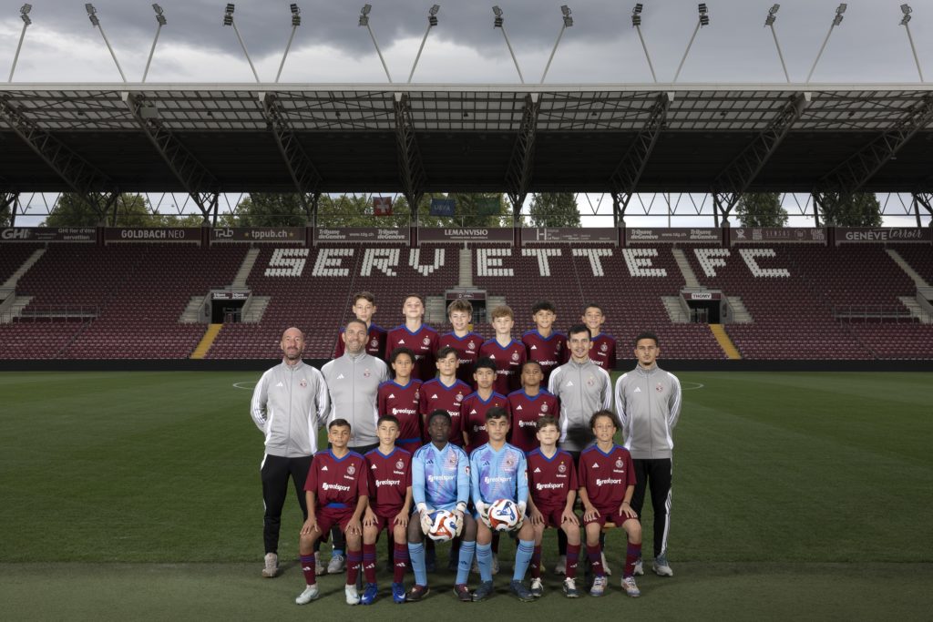 Photo officielle de l’équipe FE13 du Servette FC, prise au Stade de Genève. Les jeunes joueurs posent aux côtés de leur staff technique, incarnant l’engagement et la formation dispensée par le club.
