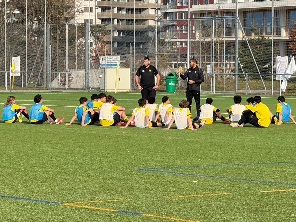 Entraîneurs et joueurs M15 GEF Meyrin FC en discussion sur le terrain à Genève.